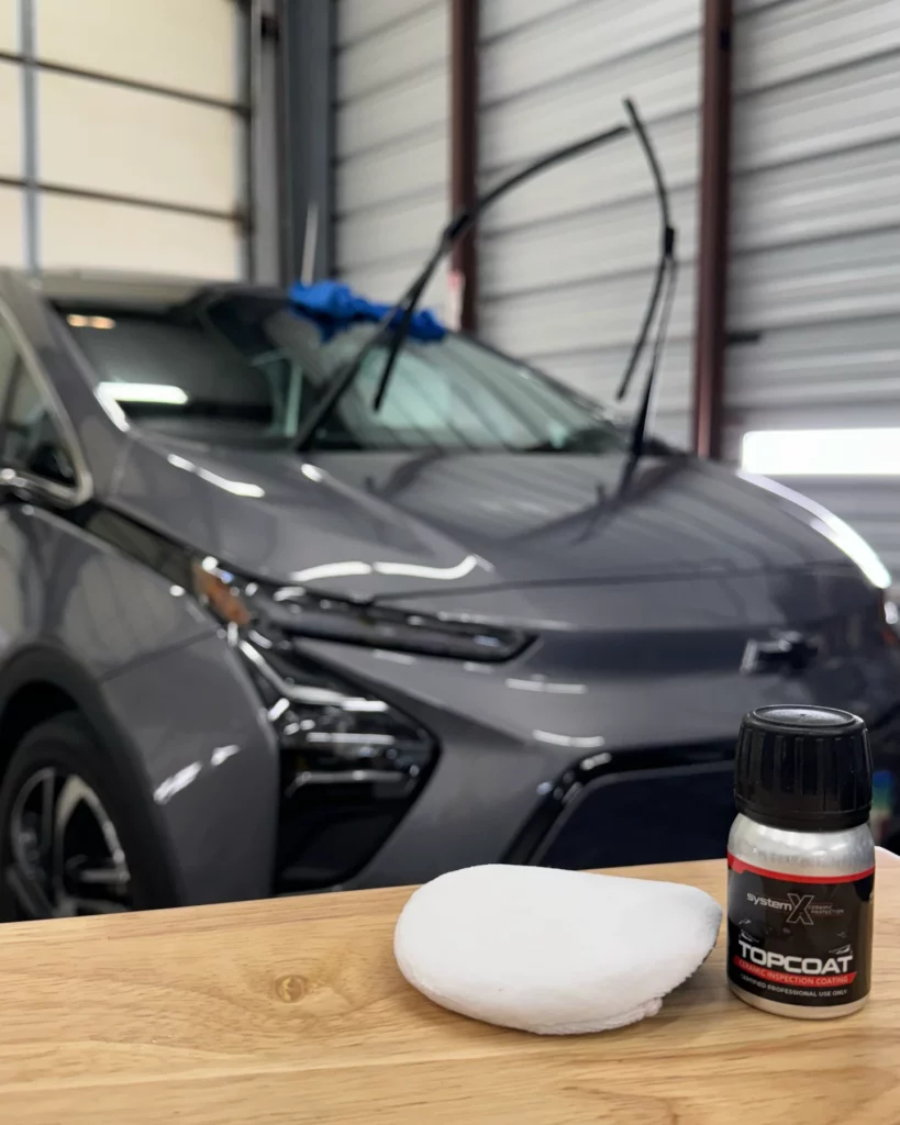 SystemX TopCoat product on table Chevrolet car in the background